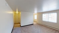 This single-floor residential unit offers a straightforward and functional layout designed for comfortable everyday living. The entry opens into a spacious living area finished with neutral wall-to-wall carpeting and clean white walls. A partial dividing wall separates the entryway from the main living space, which is brightened by multiple windows that invite natural light and provide views of the surrounding building exterior. Baseboard heating runs along the perimeter, ensuring consistent warmth throughout.

The galley-style kitchen is efficiently arranged with white cabinetry, wood-toned countertops, a gas range, a refrigerator, and a single-basin sink. Tile flooring and ample upper cabinet storage make this kitchen both practical and easy to maintain.

The bathroom features large-format tile flooring, a full soaking tub with an overhead shower, a wall-mounted sink, and a window that provides natural ventilation and light, all set against a clean white finish.

The bedrooms are carpeted and generously sized, each benefiting from multiple windows dressed with blinds, baseboard heating, and dedicated closet space. The overall ambiance of the unit is clean, bright, and move-in ready, with a neutral palette throughout that offers a versatile backdrop for any furnishing style.