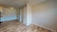 Located at 2001 Rockcreek Dr in Bowling Green, Kentucky, this single-floor unit offers a practical and comfortable layout with a clean, neutral aesthetic throughout. The living area features wood-look plank flooring and a paneled entry door, creating a welcoming and functional main space. A textured ceiling runs throughout the unit, adding subtle character to each room. The kitchen is well-appointed with white cabinetry featuring raised-panel doors and dark hardware, a double stainless steel sink, and granite-look countertops, all set atop matching wood-look flooring. Adjacent to the kitchen, the layout flows into connecting hallways and living spaces with efficient use of the available footprint. The bedrooms are carpeted with plush, neutral-toned carpet, offering a comfortable feel underfoot. One bedroom benefits from a window fitted with blinds, allowing natural light to filter in. The full bathroom is finished with tile flooring, a white vanity with cabinetry below, and a shower-tub combination framed by a decorative curtain rod. Throughout the unit, crisp white trim and baseboards provide clean contrast against the warm neutral wall tones, creating a cohesive and move-in ready environment.