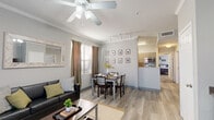 This single-story residence offers four bedrooms and two bathrooms within a thoughtfully designed floor plan. The open-concept living and dining area serves as the heart of the home, featuring light wood-style flooring, crown molding, and a ceiling fan overhead. Track lighting illuminates the dining space, while large windows allow natural light to fill the room. The kitchen is positioned adjacent to the dining area, featuring warm cabinetry, a raised bar counter, and modern appliances. A built-in media cabinet with granite-style countertop is a standout feature in one of the living areas, adding both function and style.

The four bedrooms are carpeted for comfort and vary in layout, with several featuring mirrored sliding closet doors and built-in desks. The primary bedroom includes direct access to a bathroom with a full vanity. Each bedroom offers ample natural light through window blinds. The two full bathrooms are clean and functional, each equipped with a tiled tub-shower combination. A dedicated in-unit laundry area houses a full-size washer and dryer with overhead shelving. Neutral gray tones throughout the home create a cohesive and modern aesthetic, making this residence both practical and inviting.