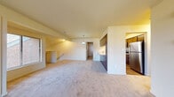 Located at 5695 Glenn Cross Rd in Battle Creek, Michigan, this single-floor residence offers a thoughtfully designed layout that balances open communal spaces with private retreats. The living area is generously sized, featuring plush carpeting, a wall-mounted fireplace, and a sliding glass door that opens to a private balcony, allowing natural light to fill the room and providing outdoor access.

The kitchen is well-equipped with dark wood cabinetry, granite-style countertops, and stainless steel appliances including a refrigerator, range, and microwave. Wood-look flooring grounds the kitchen, creating a clean contrast to the carpeted living spaces. A peninsula-style counter separates the kitchen from the main living area, enhancing the open-concept feel. A pendant light fixture adds a finishing touch overhead.

The bedroom is carpeted and comfortably proportioned, featuring a reach-in closet with a rod and shelf system, and a window that brings in natural light. The bathroom includes a dark wood vanity with a white countertop sink, a large mirror, and light flooring, maintaining a clean and functional aesthetic throughout. Staircase access is visible, suggesting additional levels or entry points within the building.