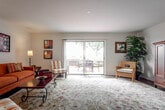 This two-story residence is thoughtfully laid out across two floors, offering a functional and comfortable living environment. The main level is anchored by a welcoming hallway finished with rich hardwood flooring that extends throughout much of the common areas. The kitchen is well-appointed with warm honey-toned cabinetry, generous counter space, recessed lighting, and a full suite of appliances including a range, microwave, and dishwasher. A pass-through opening connects the kitchen to the adjacent dining area, promoting an open, communicative flow.

The living room is a highlight of the main floor, featuring large sliding glass doors that open to a private balcony overlooking lush outdoor scenery, filling the space with natural light. A secondary sitting area provides additional flexible living space. Both living areas are finished with plush carpeting, adding warmth and comfort.

The bedrooms are generously proportioned, also carpeted, and offer a calm, restful atmosphere. The bathrooms are finished with white vanities, large mirrors, and tub-shower combinations. Hardwood flooring appears in at least one bathroom, complementing the overall design continuity found throughout the residence.