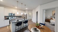 Located in Broomfield, Colorado, this well-appointed 2-bedroom, 1-bathroom residence offers a thoughtfully designed single-level layout with modern finishes throughout. The open-concept kitchen and living area serves as the heart of the home, showcasing white shaker cabinetry, dark granite countertops, a hexagonal tile backsplash, and a full suite of stainless steel appliances including a French door refrigerator, electric range, built-in microwave, and dishwasher. A kitchen island with bar seating and pendant lighting adds both function and style, flowing seamlessly into the dining and living areas. Wood-look flooring runs throughout the main living spaces, while an elegant arched passageway adds architectural character to the hallway. The primary bedroom is generously sized with plush carpet, a ceiling fan, a bright window, and access to a spacious walk-in closet with built-in shelving. The second bedroom also features carpet and a ceiling fan. The full bathroom offers a granite-topped vanity, wood-look tile flooring, and a tub-shower combination with stylish tile surround. A dedicated in-unit laundry area adds everyday convenience, rounding out this functional and attractively finished Broomfield residence.