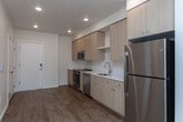 Located at 13450 W Baldcypress St in Boise, Idaho, this 1-bedroom, 1-bathroom unit offers a clean, modern design across a single floor. The open-concept living and kitchen area is anchored by warm wood-style flooring that runs throughout the main living spaces, creating a cohesive and inviting atmosphere. Recessed lighting illuminates the interior, while a wall-mounted mini-split system provides efficient climate control.

The kitchen is thoughtfully designed with light natural wood cabinetry, white quartz countertops, and a classic subway tile backsplash. A full suite of stainless steel appliances — including a refrigerator, range, over-the-range microwave, and dishwasher — provide modern functionality. The living area benefits from natural light through a glass door that opens to the outside.

The bedroom is a calm, carpeted retreat featuring a large window with blinds that allows ample natural light. The full bathroom is finished with a matching light wood vanity, white quartz countertop, a large mirror, and a tub-shower combination with clean white tile surround — all tied together by the same warm wood-style flooring. This unit presents a cohesive, contemporary aesthetic throughout.