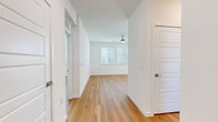 This well-appointed two-bedroom, two-bathroom single-story home in Hutto, Texas, offers a clean, modern aesthetic throughout. Light-toned hardwood flooring flows seamlessly across the entire living space, creating a cohesive and inviting atmosphere. The open-concept kitchen and living area serves as the heart of the home, featuring a peninsula with a crisp white quartz countertop, white shaker upper cabinets, and contrasting slate-blue lower cabinets. Stainless steel appliances—including a side-by-side refrigerator, range, microwave, and dishwasher—complete the kitchen. A tile backsplash and ample natural light from multiple windows add to the polished finish. The living room benefits from a ceiling fan and bright windows fitted with blinds. Both bedrooms are generously sized, each with large windows that allow natural light to fill the space, ceiling fans for comfort, and dedicated closets. The spacious primary bedroom connects to an en-suite bathroom featuring a glass-enclosed walk-in tile shower, a slate-blue vanity with quartz countertops, and a walk-in closet. The second bathroom mirrors the same refined style with a matching vanity and hardwood flooring. Throughout, the home maintains a consistent, modern palette of white walls, warm wood floors, and brushed nickel fixtures.