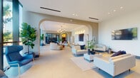 Located at 1631 NW 19th St in Miami, FL, this single-floor space presents a refined lobby and communal area defined by contemporary design and carefully considered architectural details. The layout unfolds across an expansive open floor plan finished with large-format light-toned porcelain tiles that reinforce the sense of spaciousness throughout.

Signature arched openings frame the progression through the space, creating distinct seating zones while maintaining a fluid, open atmosphere. Recessed lighting and a modern sputnik-style chandelier provide layered illumination, complementing the neutral palette of warm whites and greiges across the walls and furnishings. Multiple seating arrangements, featuring clean-lined sofas and accent chairs in light upholstery with navy accents, are thoughtfully distributed to encourage both social interaction and quieter moments.

A dedicated refreshment station is built into one wall, featuring dark marble-veined stone surfaces atop warm wood cabinetry with brushed gold hardware, offering a polished and functional amenity. Floor-to-ceiling glass curtain walls along one elevation flood the space with natural light while framing views of the surrounding Miami streetscape and lush tropical palms. A reception area with pendant lighting and controlled entry further anchors the lobby's functional role within the building.