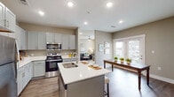 This single-floor residence is designed with a contemporary, open-concept layout that promotes a seamless flow between living spaces. The kitchen serves as a central hub, featuring gray shaker-style cabinetry, white quartz countertops, and a full suite of stainless steel appliances, including a refrigerator, electric range, microwave, and dishwasher. A central island with seating provides additional workspace and a casual dining option. Recessed lighting illuminates the kitchen, which opens directly into a dining area and living room. The living room benefits from natural light through windows with views to the outdoors and is equipped with a ceiling fan.

The bedrooms are carpeted and finished in warm neutral tones, each offering ceiling fans or adequate lighting. One bedroom features a walk-in closet outfitted with wire shelving for organized storage. The bathrooms include white vanity cabinetry, quartz countertops, large mirrors, and wood-look flooring. Throughout the main living areas, durable wood-look plank flooring ties the space together. A dedicated entryway with panel-style interior doors and a central HVAC vent above completes the practical, well-appointed design of this residence.