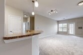 Located in Virginia Beach, VA, this single-floor home offers four bedrooms and two full bathrooms within a well-organized, functional layout. The open-concept living and dining area is finished with plush carpeting, neutral-toned walls, and a track lighting fixture, while large windows and a glass-paneled door flood the space with natural light and create an airy, welcoming ambiance. A curved kitchen island with a granite-style countertop connects seamlessly to the living area, making it ideal for entertaining. The kitchen is fully equipped with warm wood cabinetry, stainless steel appliances including a range, microwave, and refrigerator, and durable tile flooring. The spacious primary bedroom features soft carpeting and ample room, complemented by a walk-in closet outfitted with wire shelving systems for organized storage. The secondary bedrooms are equally comfortable, each carpeted and brightened by windows with blinds. Both bathrooms are finished with tile flooring, wood-toned vanity cabinetry, white countertops, and a tub-shower combination. A dedicated hallway and entrance area complete the home's thoughtful floor plan, offering a cohesive and comfortable living experience throughout.