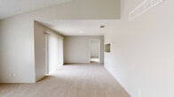 This single-story, 2-bedroom, 2-bathroom residence offers a practical and comfortable layout designed to maximize everyday living. The combined kitchen and living room serves as the heart of the home, featuring plush wall-to-wall carpeting, a ceiling fan, and a large sliding glass door dressed with vertical blinds that allows natural light to fill the space. A built-in shelf niche adds a functional architectural detail to the living area.

The primary bedroom is a well-proportioned retreat featuring vaulted ceilings, a ceiling fan with light fixture, a dedicated closet, and an en-suite bathroom. The en-suite includes a vanity with under-cabinet storage, stone-look tile flooring, and a full tub-shower combo. The second bedroom also offers carpeted flooring, natural light from a window with blinds, and its own closet access.

Both bathrooms are finished with warm-toned stone-look tile floors and white vanity cabinetry with countertops. The home also includes a pantry and three closets in total, providing ample storage throughout. Textured ceilings are consistent across the space, and the neutral warm-beige color palette lends a clean, cohesive aesthetic to every room.