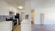 Located at 8561 De Soto Ave in the Canoga Park neighborhood of Los Angeles, this single-floor unit offers a clean, modern aesthetic with thoughtfully updated interiors. The kitchen is a standout feature, outfitted with crisp white shaker cabinetry extending to the ceiling, a mosaic tile backsplash, stainless steel gas range, stainless steel refrigerator, and a white quartz countertop peninsula that provides both prep space and a natural divider between the kitchen and the adjoining living area. The living area is generously proportioned, featuring light gray wood-look flooring that flows seamlessly throughout the unit, bright white walls, and a large window that invites natural light into the space. The open layout between the kitchen and living area creates an easy, connected flow well-suited for everyday living. The bathroom features a full soaking tub with a combined shower, brushed nickel fixtures, and a clean, minimalist design. The bedroom is a well-sized, light-filled room with vertical blinds on the window and the same consistent wood-look flooring. The unit's neutral color palette and modern finishes provide a versatile backdrop that accommodates a variety of interior styles.