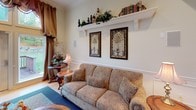 Located at 3298 Jacksonville Rd in Bethlehem, PA, this single-floor community clubhouse is thoughtfully designed to offer residents a welcoming and versatile gathering space. The layout encompasses a variety of well-appointed rooms, each contributing to the overall warmth and functionality of the facility.

The main lounge area exudes classic elegance, featuring hardwood flooring, crown molding, wainscoting, and a wood-burning fireplace. A comfortable upholstered sofa, decorative artwork, and a built-in wooden entertainment center with display shelving create an inviting atmosphere for relaxation. French doors with glass panes connect the spaces, enhancing the sense of openness and flow throughout.

The game and activity room is generously sized, offering multiple dining-height tables and chairs set atop patterned carpeting. Large windows with ornate valances frame views of the surrounding greenery, filling the room with natural light. A large mirror accentuates the sense of space, while a built-in bookcase adds a refined touch.

The galley-style kitchen is bright and functional, outfitted with white cabinetry, a full suite of appliances, and ample counter space — well-suited for catering and community events.

The fitness room is equipped with Cybex cardio machines and features natural light from multiple windows. A well-appointed full bathroom with floral wallcovering and tile flooring rounds out the amenities of this charming community space.