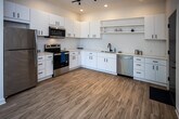 Located at 2004 City Vista Way in Knoxville, Tennessee, this single-floor residence offers a clean, contemporary design with thoughtful finishes throughout. The kitchen is a standout feature, showcasing white shaker-style cabinetry with matte black hardware, light quartz countertops, a matte black faucet with an undermount sink, open shelving, and a full suite of stainless steel appliances including a refrigerator, electric range, over-the-range microwave, and dishwasher. Light wood-look flooring and track lighting complete the kitchen's modern aesthetic. The primary bedroom is generously proportioned, featuring soft carpeting, crown molding, a ceiling fan, and a stylish sliding barn door that opens to a walk-in closet. An additional bedroom offers plush carpeting, a ceiling fan, and a large window that fills the room with natural light and garden views. The bathroom maintains the home's modern sensibility with a white vanity, light countertop, wood-look flooring, and a walk-in shower enclosed by a black-framed glass door. Throughout the residence, a cohesive palette of neutral tones, matte black accents, and light flooring creates a bright, inviting atmosphere well-suited to contemporary living.