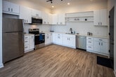 Located at 2004 City Vista Way in Knoxville, Tennessee, this single-floor residence offers a clean, contemporary design with thoughtful finishes throughout. The kitchen is a standout feature, showcasing white shaker-style cabinetry with matte black hardware, light quartz countertops, a matte black faucet with an undermount sink, open shelving, and a full suite of stainless steel appliances including a refrigerator, electric range, over-the-range microwave, and dishwasher. Light wood-look flooring and track lighting complete the kitchen's modern aesthetic. The primary bedroom is generously proportioned, featuring soft carpeting, crown molding, a ceiling fan, and a stylish sliding barn door that opens to a walk-in closet. An additional bedroom offers plush carpeting, a ceiling fan, and a large window that fills the room with natural light and garden views. The bathroom maintains the home's modern sensibility with a white vanity, light countertop, wood-look flooring, and a walk-in shower enclosed by a black-framed glass door. Throughout the residence, a cohesive palette of neutral tones, matte black accents, and light flooring creates a bright, inviting atmosphere well-suited to contemporary living.