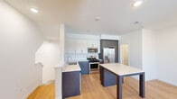Located at 9865 Graduate Drive in San Diego, CA, this contemporary three-bedroom, two-bathroom multi-story home offers a thoughtfully designed layout spread across three floors. The entry-level features an attached garage with an automatic opener and polished concrete floors, providing convenient and secure parking. The main living floor showcases an open-concept kitchen and living area highlighted by light hardwood flooring and recessed lighting throughout. The kitchen is a standout, featuring a two-tone cabinetry design with white upper cabinets and dark lower cabinets, stainless steel appliances including a gas range, built-in microwave, and French door refrigerator, complemented by a large center island with a sleek quartz countertop. A sliding glass door opens to a private balcony with neighborhood views, filling the space with natural light. The upper floor hosts three bedrooms, including a spacious primary bedroom, all finished with plush carpeting and window blinds. The bathrooms are elegantly appointed, with the full bath featuring a double-sink vanity with dark wood cabinetry, quartz countertops, dual round mirrors, and a glass-enclosed walk-in shower. Additional closet space and multiple staircases ensure practical functionality throughout this clean, modern home.