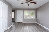 Located at 1404 Whispering Pines Rd in Albany, Georgia, this single-story home offers a clean, functional layout finished with consistent light wood-look flooring throughout. Neutral gray and taupe wall tones create a cohesive, understated aesthetic across all rooms.

The living area is bright and welcoming, featuring a ceiling fan with light fixture, a textured ceiling, and a front-facing window that draws in natural light. The space flows naturally toward the entryway, which includes a classic white door with a sidelight window.

The kitchen is equipped with white upper and lower cabinetry, a double-basin stainless steel sink, a white electric coil-burner range with overhead ventilation, and a black dishwasher. A window with blinds above the counter provides additional natural light and outward views.

The bedrooms are generously proportioned, each with ceiling fans, neutral walls, and ample natural light from windows with blinds. Closet access is provided via paneled white doors, with at least one bedroom featuring a walk-in or reach-in closet.

The bathroom includes a single-sink vanity with white cabinetry, a wall mirror, and a tiled shower-tub combination. Wood-look flooring extends into the bathroom, maintaining design continuity throughout the home.