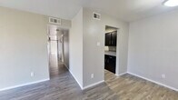 This single-story, 4-bedroom, 2-bathroom home offers a practical and efficiently designed floor plan that maximizes every square foot. Wood-look plank flooring flows consistently throughout the living areas and bedrooms, lending a cohesive and modern aesthetic across the home.

The living room is bright and open, featuring a large sliding glass door with vertical blinds that allows abundant natural light to fill the space. Adjacent to it, the dining area provides a seamless transition between living and kitchen areas.

The galley-style kitchen is a standout feature, offering dark espresso cabinetry lining both sides, speckled gray countertops, a double-basin sink, and black appliances including a gas range and refrigerator — delivering a bold, contemporary contrast to the neutral tones found throughout the rest of the home.

A long central hallway connects the four bedrooms, each finished with the same wood-look flooring and neutral wall tones. Several bedrooms feature large windows with horizontal blinds, inviting natural light into each room.

The two bathrooms are functionally designed, each featuring a full tub-shower combination with white tile surround, matching dark vanity cabinetry, speckled countertops, and clean chrome fixtures — consistent with the home's overall design language.