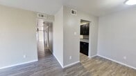 This single-story, 4-bedroom, 2-bathroom home offers a practical and efficiently designed floor plan that maximizes every square foot. Wood-look plank flooring flows consistently throughout the living areas and bedrooms, lending a cohesive and modern aesthetic across the home.

The living room is bright and open, featuring a large sliding glass door with vertical blinds that allows abundant natural light to fill the space. Adjacent to it, the dining area provides a seamless transition between living and kitchen areas.

The galley-style kitchen is a standout feature, offering dark espresso cabinetry lining both sides, speckled gray countertops, a double-basin sink, and black appliances including a gas range and refrigerator — delivering a bold, contemporary contrast to the neutral tones found throughout the rest of the home.

A long central hallway connects the four bedrooms, each finished with the same wood-look flooring and neutral wall tones. Several bedrooms feature large windows with horizontal blinds, inviting natural light into each room.

The two bathrooms are functionally designed, each featuring a full tub-shower combination with white tile surround, matching dark vanity cabinetry, speckled countertops, and clean chrome fixtures — consistent with the home's overall design language.