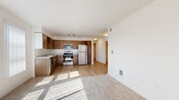 Located on E Burnside Street in Portland, OR, this single-floor, 2-bedroom, 2-bathroom residence offers a thoughtfully arranged layout that makes efficient use of its space. The open-concept kitchen and living area serves as the heart of the home, bathed in natural light streaming through large windows with vertical blinds. The kitchen is well-equipped with warm wood-tone cabinetry, light countertops, and a full suite of stainless steel appliances including a refrigerator, range, microwave, and dishwasher, all set atop durable light wood-style flooring. The living area transitions seamlessly from hard flooring to plush carpet, creating a comfortable and inviting atmosphere. The spacious primary bedroom features soft carpeting, ample natural light from a window with outdoor views of greenery, and a dedicated closet with built-in wire shelving. The second bedroom is equally well-appointed with carpet flooring and closet access. Both bathrooms are finished cleanly in white, with one featuring a full soaking tub with curved shower rod, a wood-toned vanity, and light wood flooring. A connecting hallway with recessed lighting ties the rooms together, completing this clean, modern, and functional home.