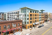 Exterior view of a modern apartment building with mixed facade materials and balconies, on a sunny day.
