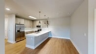 Located at 10811 Colonial Gateway Dr in Fort Myers, FL, this well-appointed 3-bedroom, 1-bathroom single-story home offers a thoughtfully designed layout with modern finishes throughout. The open-concept kitchen and living area serves as the heart of the home, anchored by a generous peninsula with a crisp white countertop, undermount sink, and stylish brushed nickel pendant lights. Light wood-toned cabinetry, a classic white subway tile backsplash, and stainless steel appliances — including a French door refrigerator, range, and microwave — complete the contemporary kitchen aesthetic. Warm wood-look flooring flows seamlessly through the main living areas, adding cohesion and a clean, modern feel. A well-lit hallway with recessed lighting connects the bedrooms, each finished with plush carpeting and dedicated closet space. The spacious primary bedroom features natural light through sizable windows and its own closet. The full bathroom is finished with wood-look vinyl flooring, a subway-tiled tub and shower surround, and bright, clean fixtures. Neutral gray tones on the walls throughout the home create a calm, versatile backdrop. This home's practical single-floor layout and modern design details make it a comfortable and functional residence in Fort Myers.