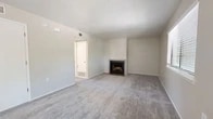Located at 4201 Meadowlark Ln SE in Rio Rancho, New Mexico, this single-floor, 2-bedroom, 2-bathroom home offers a practical and comfortable layout with clean, neutral finishes throughout. The open living room serves as the heart of the home, anchored by a tile-surround fireplace with a classic black insert, plush carpet, and a window that brings in natural light. The kitchen flows directly from the living area and features white cabinetry, granite-style countertops, wood-look flooring, and stainless steel appliances including a range and dishwasher. Both bedrooms are carpeted and include ceiling fans with light fixtures and dedicated closets with built-in shelving and hanging rods — the primary bedroom offering a notably generous footprint. The two bathrooms are finished with wood-look flooring and include a tub-shower combo in one and clean, minimal fixtures throughout both. A hallway connects the rooms efficiently, and two closets provide ample storage. The textured ceilings and consistent neutral color palette lend a cohesive, understated aesthetic to the entire home.