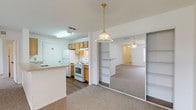 This single-story residence offers a practical and well-organized layout designed for comfortable everyday living. The kitchen is laid out in a galley style, featuring light oak cabinetry with ample upper and lower storage, laminate countertops, a single-basin sink, a white electric range with overhead ventilation, and a full-size refrigerator. Wood-look flooring runs throughout the kitchen, adding a warm contrast to the white appliances and walls.

The living area is generously proportioned, finished with neutral carpet and a ceiling fan overhead. A built-in shelving unit and mirrored sliding closet doors add both function and visual depth to the space, while pendant lighting provides a focal point near the kitchen transition.

Multiple bedrooms are carpeted and bright, each equipped with ceiling fans and windows that bring in natural light and outdoor views. Closets with louvered doors provide dedicated storage in each room.

The bathrooms feature wood-look flooring, oak vanity cabinetry, framed mirrors with overhead lighting, and a tub-shower combination. A hallway connects the living spaces to the private areas of the home, creating a clear and efficient flow throughout the single-floor layout.