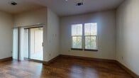 This single-floor unit offers a well-designed open layout highlighted by rich, dark hardwood flooring that flows throughout the main living areas. The spacious living room is bathed in natural light from large windows fitted with white blinds, and features a ceiling fan, track lighting, and a sliding glass door leading to a private balcony with outdoor views.

The kitchen is a standout feature, showcasing dark cabinetry that extends to the ceiling, a mosaic tile backsplash, granite countertops, and a white central island with pendant lighting overhead. Stainless steel appliances — including a refrigerator, electric range, and built-in microwave — complete the kitchen's modern, functional design.

The bedroom features plush carpeting, ample natural light from dual windows, and a sliding barn-style door that adds a contemporary touch. The bathroom includes wood-look flooring, a granite-topped dark vanity, a full soaking tub with classic white subway tile surround, and access to a walk-in closet with wire shelving.

A dedicated in-unit laundry area houses a full-size washer and dryer with overhead shelving. The unit's neutral wall tones and cohesive finishes create a clean, modern ambiance throughout.