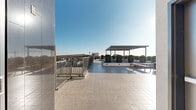 Located in the heart of East Hollywood, this rooftop terrace at 5460 Fountain Ave offers an open-air retreat with panoramic views of the Hollywood Hills, the surrounding Los Angeles skyline, and notable neighborhood landmarks. The terrace is finished with large-format, light-toned pavers that extend across the entire deck, lending a clean and contemporary aesthetic underfoot.

A prominent slatted pergola anchors a central gathering zone, providing partial shade over a set of long wooden communal tables flanked by matching benches — an ideal setup for outdoor dining or social events. Surrounding the seating area, a series of oversized cylindrical planters filled with manicured topiary shrubs are arranged on gravel-lined raised platforms, adding structured greenery and a refined landscape design to the space.

The perimeter of the terrace is secured by metal railings that frame unobstructed views in multiple directions, including striking sightlines toward a distinctive Russian Orthodox church dome visible to the south. Wood-slat privacy screens offer a warm contrast to the industrial-modern elements present throughout. The deck receives abundant natural sunlight throughout the day, making it a bright and inviting outdoor space well-suited for community gatherings, events, or relaxed open-air use in the Los Angeles climate.