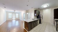 Located at 1901 S Charles St in Baltimore's South Baltimore neighborhood, this two-bedroom, one-bathroom residence offers a well-designed single-floor layout with a comfortable and functional living environment. The open-concept kitchen and living area serves as the heart of the home, where rich dark cabinetry contrasts elegantly with light granite countertops. A peninsula island with a built-in wine rack and pendant lighting above adds both style and practicality. Stainless steel appliances, including a refrigerator, range, microwave, and dishwasher, complete the kitchen. The living area features warm hardwood flooring and natural light from windows overlooking the surroundings. The two bedrooms are carpeted and offer a quiet retreat, with the primary bedroom providing a generous footprint and dual windows for natural light. A dedicated closet provides additional storage. The full bathroom includes a tiled tub-shower combination, a dark-cabinetry vanity with granite countertop, and tile flooring consistent with the kitchen's aesthetic. A utility corridor with tile flooring connects key areas of the home, adding to its efficient layout. Neutral wall tones throughout create a clean, move-in-ready atmosphere suited for a variety of lifestyles.