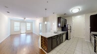 Located at 1901 S Charles St in Baltimore's South Baltimore neighborhood, this two-bedroom, one-bathroom residence offers a well-designed single-floor layout with a comfortable and functional living environment. The open-concept kitchen and living area serves as the heart of the home, where rich dark cabinetry contrasts elegantly with light granite countertops. A peninsula island with a built-in wine rack and pendant lighting above adds both style and practicality. Stainless steel appliances, including a refrigerator, range, microwave, and dishwasher, complete the kitchen. The living area features warm hardwood flooring and natural light from windows overlooking the surroundings. The two bedrooms are carpeted and offer a quiet retreat, with the primary bedroom providing a generous footprint and dual windows for natural light. A dedicated closet provides additional storage. The full bathroom includes a tiled tub-shower combination, a dark-cabinetry vanity with granite countertop, and tile flooring consistent with the kitchen's aesthetic. A utility corridor with tile flooring connects key areas of the home, adding to its efficient layout. Neutral wall tones throughout create a clean, move-in-ready atmosphere suited for a variety of lifestyles.