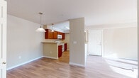 Located at 3105 East Assembly Road in Spokane, WA, this single-floor residence offers a thoughtfully designed layout with an open and airy feel throughout. The main living area features warm hardwood-style flooring and is bathed in natural light streaming through sliding glass doors that lead to a private outdoor balcony, offering pleasant views of the surrounding neighborhood and evergreen trees.

The kitchen is well-equipped with rich cherry wood cabinetry, light countertops, and white appliances including a range, microwave, refrigerator, and dishwasher. A peninsula with pendant lighting connects seamlessly to the dining and living areas, making the space ideal for both everyday living and entertaining. The entry foyer opens naturally into this combined living and kitchen zone.

The bedrooms are carpeted for comfort, each featuring windows with outdoor views that bring in ample natural light. One bedroom includes a built-in closet with sliding panel doors. The two bathrooms are finished with hardwood-style flooring, wood-toned vanity cabinetry, and full bathtub-shower combinations. Neutral warm beige tones are carried throughout the residence, creating a cohesive and inviting ambiance from room to room.