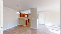 Located at 3105 East Assembly Road in Spokane, WA, this single-floor residence offers a thoughtfully designed layout with an open and airy feel throughout. The main living area features warm hardwood-style flooring and is bathed in natural light streaming through sliding glass doors that lead to a private outdoor balcony, offering pleasant views of the surrounding neighborhood and evergreen trees.

The kitchen is well-equipped with rich cherry wood cabinetry, light countertops, and white appliances including a range, microwave, refrigerator, and dishwasher. A peninsula with pendant lighting connects seamlessly to the dining and living areas, making the space ideal for both everyday living and entertaining. The entry foyer opens naturally into this combined living and kitchen zone.

The bedrooms are carpeted for comfort, each featuring windows with outdoor views that bring in ample natural light. One bedroom includes a built-in closet with sliding panel doors. The two bathrooms are finished with hardwood-style flooring, wood-toned vanity cabinetry, and full bathtub-shower combinations. Neutral warm beige tones are carried throughout the residence, creating a cohesive and inviting ambiance from room to room.