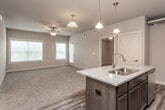 This single-floor unit offers a thoughtfully designed open-concept layout that seamlessly connects the living area to the kitchen. The living space features plush carpeting, a ceiling fan, and neutral gray walls that create a clean, versatile backdrop. Pendant lighting above the kitchen island adds a warm, inviting touch as the space transitions from carpet to durable wood-look vinyl flooring.

The kitchen is well-appointed with dark espresso cabinetry, granite-look countertops, a central island, and a full suite of stainless steel appliances including a refrigerator, range, and microwave. A dedicated pantry with built-in shelving provides ample storage. Exposed cylindrical ductwork running across the ceiling adds an industrial character to the space.

The bedrooms are carpeted and sized generously, each equipped with a ceiling fan and windows fitted with blinds that allow for natural light. The bathrooms are finished with wood-look vinyl flooring, dark vanity cabinetry, white countertops, and brushed nickel fixtures. One bathroom includes a tub/shower combination, while the other features a single vanity with a large mirror. The overall ambiance is modern, clean, and functional.