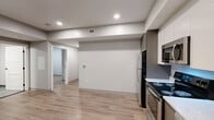 Located at 100 Hemenway Street in Boston's Fenway neighborhood, this two-bedroom, one-bathroom unit offers a thoughtfully designed, modern living space. The open-plan layout seamlessly connects the kitchen, dining, and living areas, all finished with light wood-style flooring and recessed lighting that keeps the space feeling bright and airy. The kitchen is well-appointed with two-tone cabinetry—white upper cabinets paired with taupe lowers—complemented by light stone countertops and a full suite of stainless steel appliances, including a refrigerator, electric range, microwave, and dishwasher. Both bedrooms feature soft carpeting and are equipped with wall-mounted split AC units for individual climate control. Natural light enters through double windows, and each bedroom is served by ample closet space, including a double-door closet. The bathroom is cleanly finished with large-format gray tile flooring and a walk-in shower clad in classic white subway tile. Three closets throughout the unit provide generous storage. The neutral color palette, clean lines, and modern fixtures throughout give this unit a contemporary, move-in-ready aesthetic well-suited to urban living in Boston.