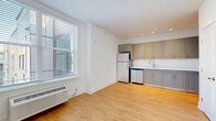 Located at 1001 W Elizabeth Ave in Linden, NJ, this one-bedroom, one-bathroom unit offers a thoughtfully designed layout that maximizes every inch of its compact footprint. The open-concept living, dining, and kitchen area is bright and welcoming, featuring warm hardwood-style flooring that runs throughout the entire unit and large windows that invite generous natural light. A wall-mounted HVAC unit ensures year-round comfort.

The kitchen is well-appointed with grey shaker-style cabinetry extending to the upper and lower walls, a classic white subway tile backsplash, light countertops, and a full suite of stainless steel appliances including a refrigerator, dishwasher, range, and microwave — all illuminated by sleek track lighting overhead.

The bedroom is a comfortable, well-proportioned retreat with soft neutral-toned walls, its own window with natural light, and a wall-mounted HVAC unit. Three closets throughout the unit provide excellent storage capacity.

The bathroom features a frameless glass walk-in shower with tile surround, a grey vanity with a stone-style countertop, and matching hardwood-style flooring. A dedicated laundry area adds everyday convenience. Clean white walls and crisp baseboards throughout give the unit a fresh, modern aesthetic.