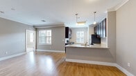 Located at 111 Holling Dr in Frederick, Maryland, this well-appointed 2-bedroom, 3-bathroom residence offers a thoughtfully designed single-level layout. The open-concept living and kitchen area serves as the heart of the home, bathed in natural light from multiple windows dressed with classic plantation shutters. Crown molding adds a refined architectural touch throughout the main living spaces, which feature warm hardwood-style flooring.

The kitchen is a standout, showcasing rich dark-espresso cabinetry, granite countertops, a classic subway tile backsplash, and stainless steel appliances. A peninsula with pendant lighting provides additional counter space and casual seating, seamlessly connecting the kitchen to the living area.

Both bedrooms are generously proportioned, with plush carpeting and large windows that invite natural light. The primary bedroom includes a ceiling fan and direct access to an en-suite bathroom. The bathrooms are finished with tile flooring, dark wood vanities, and brushed nickel fixtures, with one featuring a full tub-shower combination.

A connecting hallway ties the rooms together with practicality and flow. The neutral warm-gray palette throughout creates a cohesive, calm ambiance, making this a comfortable and move-in-ready residence in Frederick, MD.