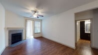 This single-floor residence offers a well-designed layout with a cohesive mix of materials and finishes throughout. The living area features rich hardwood-style flooring, a ceiling fan with light fixture, and a fireplace along one wall. Natural light enters through blinds-fitted windows, and a glass door provides access to an outdoor area, adding a sense of openness to the space.

The kitchen is a standout feature, equipped with dark espresso-toned cabinetry, granite countertops, and stainless steel appliances including a refrigerator, microwave, and range. A central island with a matching granite surface provides additional prep space and is illuminated by elegant pendant lights. Track lighting above adds functional brightness to the workspace.

The bedroom is carpeted for comfort, benefits from a ceiling fan, a window allowing natural light, and opens directly into a spacious walk-in closet with built-in shelving and hanging rods. The bathroom is well-appointed with a double-sink vanity featuring dark cabinetry and granite countertops, a large mirror with overhead lighting, a soaking tub, and a walk-in closet accessible from within. Additional rooms feature plush carpeting and ceiling fans, maintaining a consistent, comfortable atmosphere throughout.
