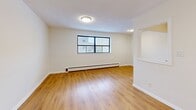Located at 2417 Hurontario Street in Mississauga, this one-bedroom, one-bathroom unit offers a well-organized single-floor layout designed for comfortable everyday living. Warm hardwood-style flooring flows throughout the main living areas and bedroom, creating a cohesive and inviting atmosphere.

The living room is generously proportioned, featuring large windows that bring in natural light and views of the surrounding neighbourhood. A baseboard heating system runs along the exterior walls, ensuring comfort year-round. The entry foyer provides a practical transition into the living space.

The galley-style kitchen is efficiently designed with light wood cabinetry, ample upper and lower storage, white countertops, a single-basin sink, and white appliances including a stove and refrigerator. Tile flooring in the kitchen distinguishes it from the rest of the unit.

The bedroom is a comfortable size, featuring a window with natural light, a radiator heating unit, and clean neutral walls. A closet with sliding doors provides practical storage. The bedroom connects conveniently to adjacent rooms, including a hallway leading to the bathroom.

The bathroom is finished with large-format beige wall tiles surrounding a full soaker tub and shower combination, complemented by a white sink vanity — clean and functional in design. Overall, the unit presents a bright, neutral palette ideal for personalization.