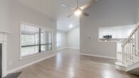 Located at 2775 Enterprise Rd E in Clearwater, Florida, this two-story residence offers a well-designed layout with a thoughtful mix of finishes throughout. The main living area impresses with soaring vaulted ceilings, light hardwood-style flooring, and large windows that invite an abundance of natural light and outdoor views. A ceiling fan adds comfort to the airy, open space, which connects seamlessly to the kitchen via a pass-through window. The kitchen is outfitted with crisp white shaker cabinetry, stone countertops, a gray subway tile backsplash, and a full suite of stainless steel appliances including a range, over-the-range microwave, and dishwasher. Textured walls and classic paneled doors are consistent throughout the home, lending a cohesive character to each space. The bedrooms feature plush carpeting, ceiling fans, and ample natural light, with one bedroom offering a corner window arrangement. The primary bathroom is equipped with a dual-sink vanity, stone countertops, gold-framed mirrors, and wood-look flooring, while a secondary bathroom provides a full tub-shower with clean white tile surround. A dedicated in-unit laundry space accommodates a full-size washer and dryer with overhead shelving for added storage. A staircase connects both levels, completing this functional and comfortable Clearwater home.