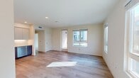 North Grove A1D is a thoughtfully designed 1-bedroom, 1-bathroom apartment spanning 740 square feet in Riverside, CA. The open-concept living area features light wood-style flooring, neutral tones, and multiple windows that flood the space with natural light while offering views of the surrounding community. The modern kitchen is a standout feature, equipped with stainless steel appliances including a French door refrigerator, gas range, built-in microwave, and dishwasher. Flat-panel cabinetry in warm wood and soft gray tones pairs with a white tile backsplash and light countertops for a clean, contemporary aesthetic. The 120 sq ft bedroom is carpeted for comfort, offering a quiet retreat with ample natural light. A dedicated walk-in closet provides generous storage with wire shelving systems lining the walls. The full bathroom features light wood-tone cabinetry with a white countertop vanity, large mirror, and a tub/shower combination with white tile surround, all set on light hardwood-style flooring. A hallway connects the rooms efficiently. The unit also includes an outdoor balcony with views of the well-maintained North Grove community courtyard and parking area.