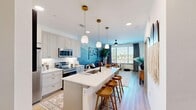 Located in Denver's Central Park neighborhood, this 1-bedroom, 1-bathroom residence offers a thoughtfully designed open-concept layout with modern finishes throughout. Light wood-style flooring flows seamlessly across the main living area, connecting the kitchen, dining, and living spaces.

The kitchen is a standout feature, equipped with stainless steel appliances, soft gray shaker cabinetry with gold hardware, a white quartz countertop island with bar seating, and elegant pendant lighting — ideal for both cooking and entertaining. A built-in desk nook provides a convenient workspace just off the kitchen.

The living room is bathed in natural light from large windows and a glass door, and features a striking mountain mural accent wall that adds a distinctive Colorado-inspired character. A ceiling fan overhead adds comfort to the space.

The bedroom is a well-proportioned retreat, featuring a bold navy accent wall, a ceiling fan, and a window with outdoor views, creating a calm and restful atmosphere. An adjacent closet provides ample storage.

The bathroom offers a clean, contemporary design with gray cabinetry, gold hardware accents, a wide vanity with a white countertop, a large mirror, and a walk-in shower with tile surround. Every room in this residence reflects a cohesive, modern aesthetic with warm, inviting touches.