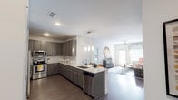 This single-story residence offers a thoughtfully designed open-concept layout connecting the kitchen, dining, and living areas. The kitchen is well-equipped with grey cabinetry, granite countertops, stainless steel appliances, a white subway tile backsplash, and a central island with pendant lighting and bar seating — ideal for both meal preparation and casual dining. Dark hardwood-style flooring runs throughout the main living areas, adding warmth and continuity.

The living room features a bold navy accent wall, crown molding, a ceiling fan, and windows that invite natural light. Two bedrooms provide comfortable retreats; one showcases a warm orange accent wall with carpeted flooring, while the other features a calming blue accent wall, also carpeted, with generous window exposure. Both rooms include ceiling fans.

The bathrooms are finished with granite-topped vanities, dark cabinetry, hardwood-style flooring, framed mirrors, and tub-shower combinations with subway tile surrounds. One bathroom provides direct access to a walk-in closet. Throughout the space, consistent use of granite surfaces, neutral tones, and quality finishes creates a cohesive and polished aesthetic.