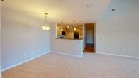 Located at 12231 Elm Forest Ct in Clarksburg, Maryland, this two-floor residence offers a well-organized layout with a variety of functional spaces spread across both levels. The main living area is immediately notable for its soaring double-height ceiling, which creates a dramatic sense of openness and volume. Soft carpeting throughout the living space adds warmth, while a pendant light fixture anchors the room. Adjacent to the living area, a kitchen features a raised breakfast bar peninsula that separates it from the main living space. The kitchen is equipped with warm-toned wood cabinetry, dark countertops, hardwood-style flooring, and black appliances including a gas range, microwave, and refrigerator. Track and pendant lighting illuminate the space effectively.

The main-level bathroom includes a tiled tub-shower combination, a vanity with storage, and hardwood-style flooring. A half-bath is also present on this level. Multiple carpeted bedrooms are found across both floors, each featuring neutral walls and windows with outdoor views of surrounding greenery. One upper-level bedroom benefits from a ceiling fan and multiple windows, while another features vaulted ceiling angles and a double-door closet. The upper floor is accessible via an interior staircase and offers a flexible loft-style configuration.