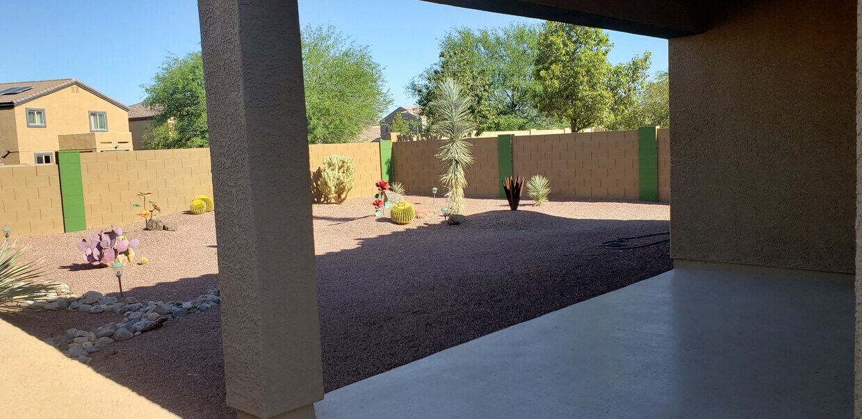 Patio trasero ordenado y ajardinado con cactus y rocas decorativas. - 8613 N Lodgepole Pine Trl