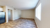 Located at 2929 N Castro Ave in Tucson, Arizona, this single-floor unit offers a clean, updated interior with a cohesive modern aesthetic throughout. Wood-look plank flooring runs continuously across the main living areas, providing a warm and durable foundation that ties the space together visually.

The open living area is generously proportioned, featuring neutral beige walls, white baseboards, and a textured ceiling. Large windows dressed with vertical blinds allow natural light to filter into the space, creating a bright and airy atmosphere. Ceiling-mounted HVAC vents ensure consistent climate control throughout.

The kitchen is a standout feature, showcasing a stylish two-tone design with white upper cabinetry and slate-blue lower cabinets paired with light countertops. Black appliances, including a full-size refrigerator and a gas range, complement the modern color scheme. Dual flush-mount ceiling fixtures provide ample overhead lighting, and the kitchen opens directly to the living area for a connected, functional flow.

The bathroom continues the blue cabinetry theme with a bold blue vanity, light stone-style countertop, and a full tub-and-shower combination with white tile surround. The 3D floor plan reveals a compact, efficiently organized layout with clearly defined living, kitchen, sleeping, and bathroom zones.