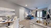 This thoughtfully designed single-story home offers three bedrooms and two bathrooms across a comfortable and efficiently laid-out floor plan. Light-toned luxury vinyl plank flooring flows through the main living areas, lending a clean and cohesive aesthetic throughout.

The open-concept kitchen and dining area form the heart of the home. The kitchen is outfitted with white shaker-style cabinetry, granite countertops, a subway tile backsplash, stainless steel appliances including a dishwasher, and a breakfast bar with a stainless steel sink. Adjacent to the kitchen, the dining area accommodates a round dining table and benefits from direct sightlines to the living room, creating a naturally connected social space.

The living room features a ceiling fan, recessed lighting, and glass French doors that open to an outdoor area, bringing in natural light and providing seamless indoor-outdoor access. The space is warm and inviting with a neutral color palette accented by soft grey tones.

The primary bedroom offers a generous layout with plush carpeting, a built-in closet, and easy access to a dedicated bathroom. Additional bedrooms are well-sized with soft carpeting and ample natural light. The bathrooms feature granite-topped vanities and tiled tub-shower combinations. A dedicated walk-in closet with wire shelving adds practical storage to the home.