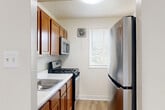 Located at 2500 Queens Chapel Rd in Hyattsville, MD, this single-floor unit offers three bedrooms and one bathroom across a well-organized layout. Light wood-style flooring runs throughout the space, lending a clean and cohesive aesthetic to every room.

The living room is generously proportioned, featuring a large window with exterior views that fills the area with natural light. Its neutral white walls and open feel create a versatile backdrop for any furnishing style. The kitchen is efficiently laid out, equipped with stainless steel appliances including a gas range and over-the-range microwave, warm-toned cabinetry, and a window overlooking greenery outside.

The primary bedroom is notably spacious, offering ample room for a full furniture arrangement, and connects to a dedicated closet. The two additional bedrooms are well-sized with windows providing natural light and outdoor views. One bedroom features a built-in closet accessible through a separate door, adding practical storage.

The bathroom is finished in an all-white palette with a vanity featuring white cabinetry, a mirror with overhead lighting, mosaic tile flooring, and a full tub-shower combination with tiled surround. The overall design of the unit is clean, neutral, and move-in ready.