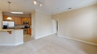This thoughtfully designed 2-bedroom, 2-bathroom residence in Greensboro, NC offers a single-floor layout that balances comfort and functionality. The open-concept living area features warm hardwood-style flooring, crown molding, and a ceiling fan, with French doors that invite abundant natural light and provide access to an outdoor balcony. Track lighting adds a modern touch to the bright, airy atmosphere.

The kitchen is well-equipped with rich dark-wood cabinetry extending to the ceiling, granite countertops, a subway tile backsplash with a decorative mosaic accent, and a full suite of stainless steel appliances including a French-door refrigerator and electric range. A breakfast bar offers additional seating and connects seamlessly to the living space.

Both bedrooms are carpeted and generously sized, each featuring a ceiling fan and windows that allow ample natural light. One bathroom includes a tiled tub-shower combination with granite vanity countertops and hardwood-style flooring, while the second bathroom is designed with accessibility in mind, featuring multiple grab bars for safety and convenience.

A carpeted hallway connects the bedrooms and provides access to both bathrooms and additional storage. The unit's neutral warm-toned palette throughout creates a cohesive, welcoming environment.