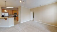 This thoughtfully designed 2-bedroom, 2-bathroom residence in Greensboro, NC offers a single-floor layout that balances comfort and functionality. The open-concept living area features warm hardwood-style flooring, crown molding, and a ceiling fan, with French doors that invite abundant natural light and provide access to an outdoor balcony. Track lighting adds a modern touch to the bright, airy atmosphere.

The kitchen is well-equipped with rich dark-wood cabinetry extending to the ceiling, granite countertops, a subway tile backsplash with a decorative mosaic accent, and a full suite of stainless steel appliances including a French-door refrigerator and electric range. A breakfast bar offers additional seating and connects seamlessly to the living space.

Both bedrooms are carpeted and generously sized, each featuring a ceiling fan and windows that allow ample natural light. One bathroom includes a tiled tub-shower combination with granite vanity countertops and hardwood-style flooring, while the second bathroom is designed with accessibility in mind, featuring multiple grab bars for safety and convenience.

A carpeted hallway connects the bedrooms and provides access to both bathrooms and additional storage. The unit's neutral warm-toned palette throughout creates a cohesive, welcoming environment.