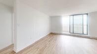 Located at 50 Burn Hill Rd in Toronto's east end, this one-bedroom, one-bathroom unit offers a clean, modern interior finished with light wood laminate flooring and crisp white walls throughout. The open-concept living room is bright and airy, bathed in natural light from a large floor-to-ceiling sliding glass door that leads directly to a private balcony, creating a seamless indoor-outdoor connection. A baseboard heating system runs along the exterior walls, ensuring comfort year-round.

The kitchen is efficiently designed, featuring white cabinetry, a classic subway tile backsplash, and stainless steel appliances including a range and over-the-range microwave. It opens directly to the living area, making the space feel connected and functional.

The bedroom is a well-proportioned, quiet retreat with a dedicated closet featuring sliding doors, a window that brings in natural light, and the same warm flooring found throughout the unit. The bathroom is finished with white subway tile surrounding a full soaker tub and shower combination, complemented by neutral tile flooring and clean fixtures.

The unit's consistent, neutral palette and modern finishes create a bright, cohesive ambiance that is both practical and inviting.