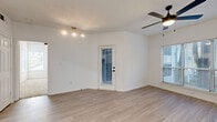 Located at 740 Sidney Marcus Blvd NE in Atlanta's 30324 zip code, this single-floor residence offers a well-appointed layout with a bright, modern aesthetic. The open living area features light wood-look flooring, crisp white walls, a textured ceiling, and a ceiling fan, with multiple windows and a glass-paneled exterior door that floods the space with natural light and provides outdoor access. An adjacent area continues the same light flooring and includes a built-in shelf and dual closet doors, offering practical storage and flexible use. The kitchen is outfitted with white shaker-style cabinetry, quartz countertops, a peninsula with a black matte sink, and stainless steel appliances including a refrigerator, range, and built-in microwave. The primary bedroom is generously sized with plush carpeting, a ceiling fan, vaulted ceilings, and abundant natural light. It connects directly to a bathroom featuring white cabinetry and a vanity. Additional bedrooms are carpeted and served by a full bathroom complete with subway-tiled tub and shower surround, light wood-look flooring, and black hardware accents. The overall design is clean and contemporary, with a consistent neutral palette that enhances the sense of openness throughout.